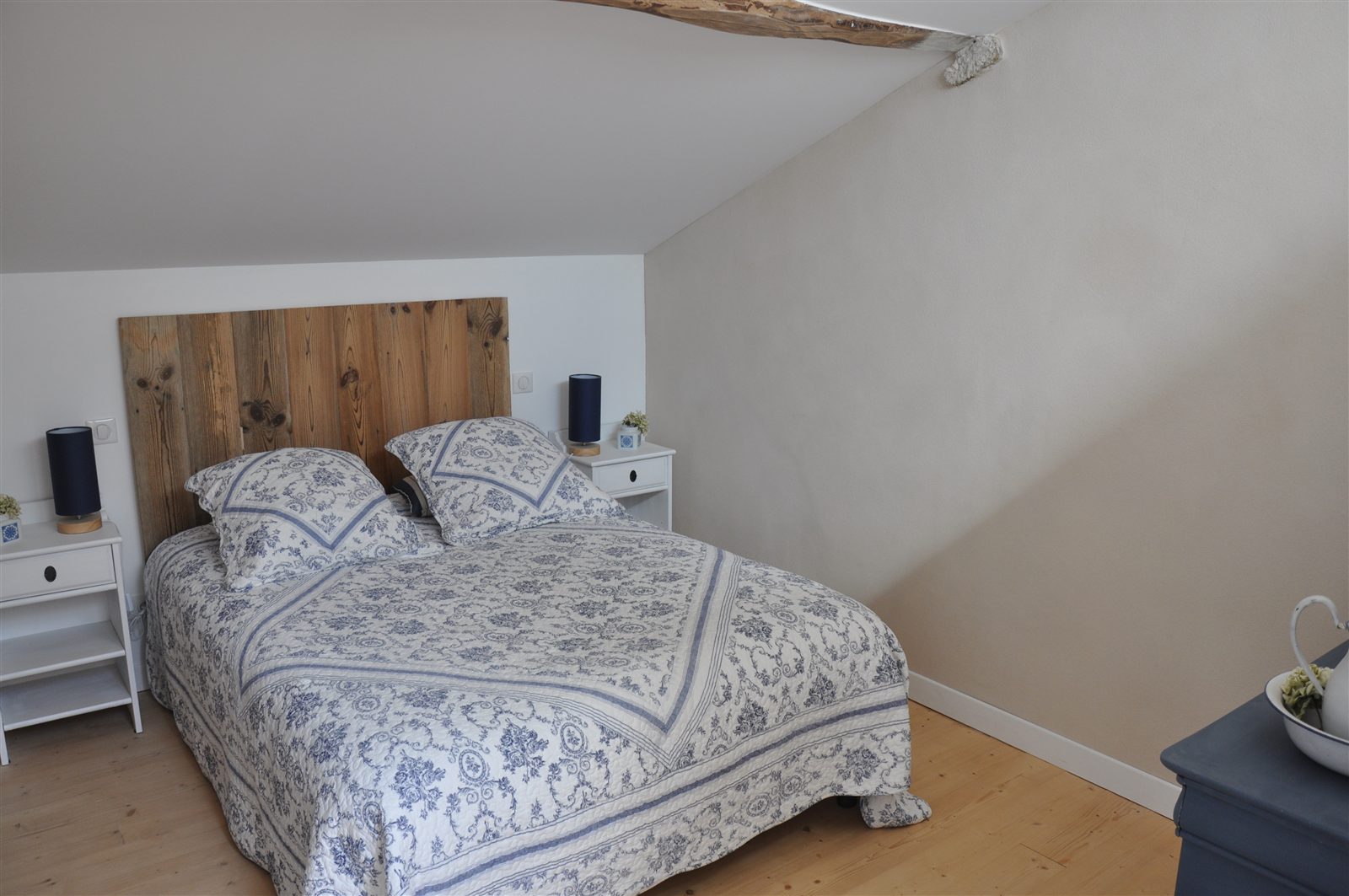 Chambre aux tons clairs, lit double et poutres apparentes