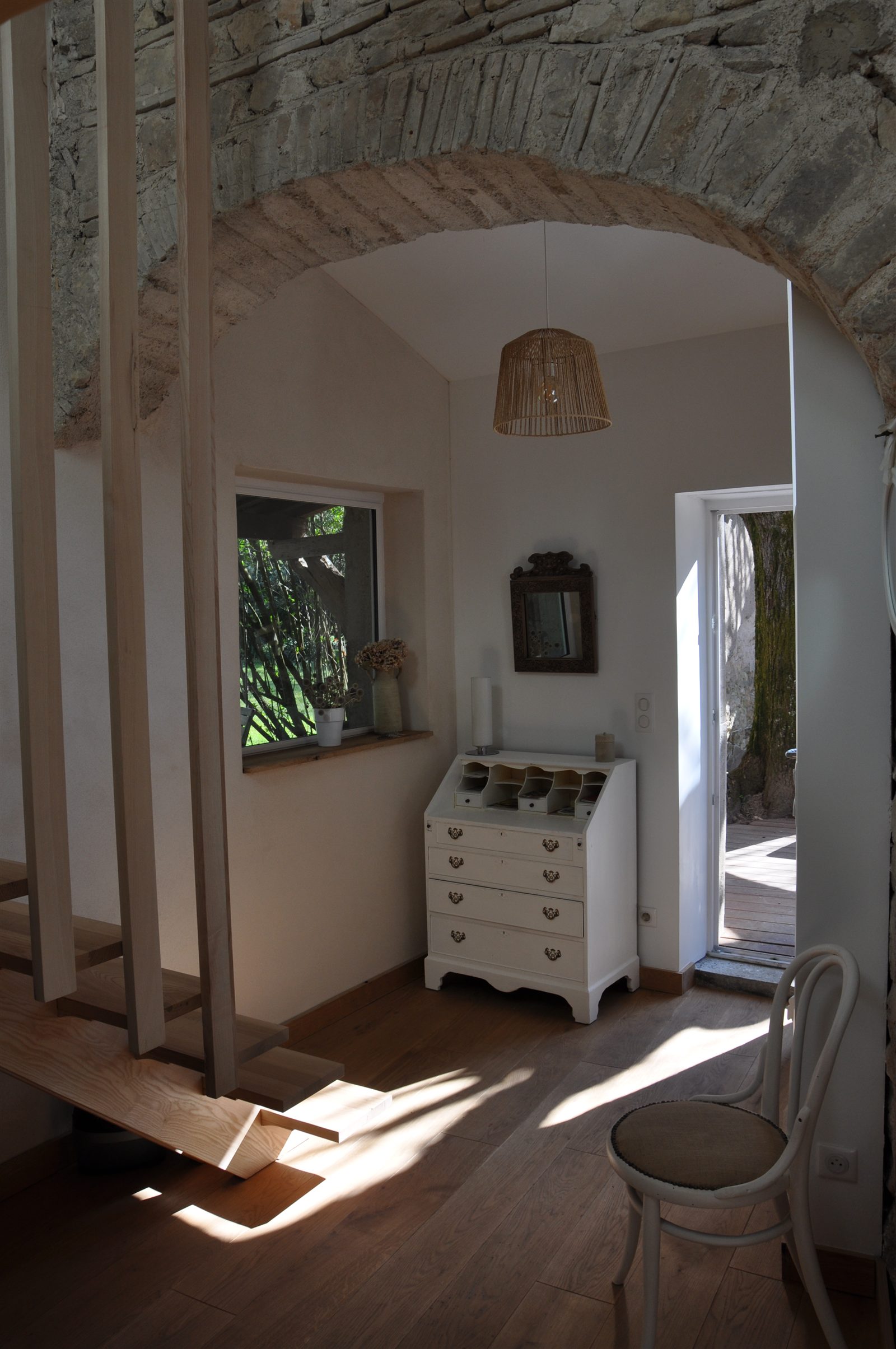 Entrée de la maison avec escalier en bois et arche en pierre
