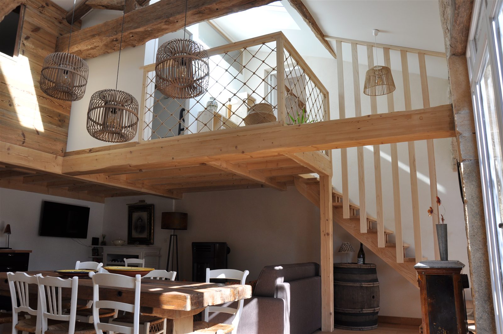 Séjour lumineux avec mezzanine, poutres et table de repas